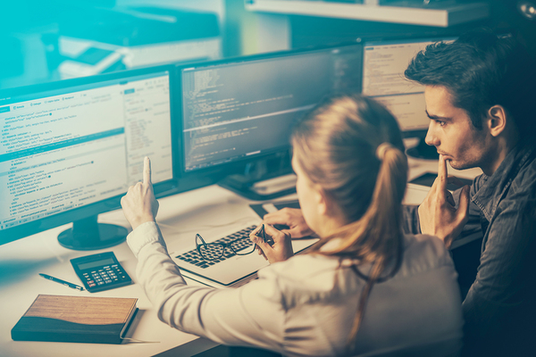 Two colleagues looking at computer screens together.